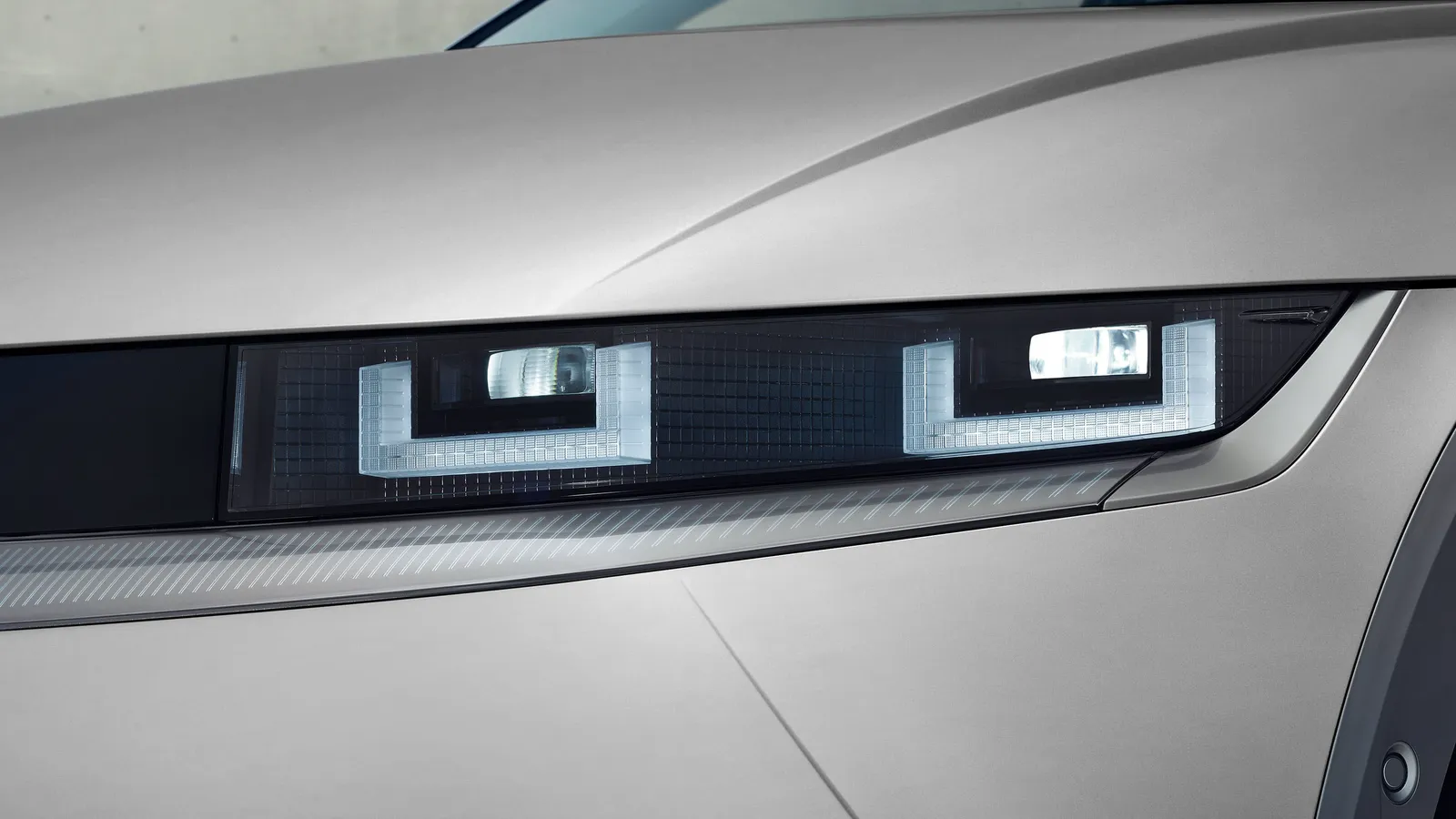Gros plan sur le phare à pixels lumineux d’un Hyundai IONIQ 5 2026 gris, allumé, carrosserie anguleuse en arrière-plan.