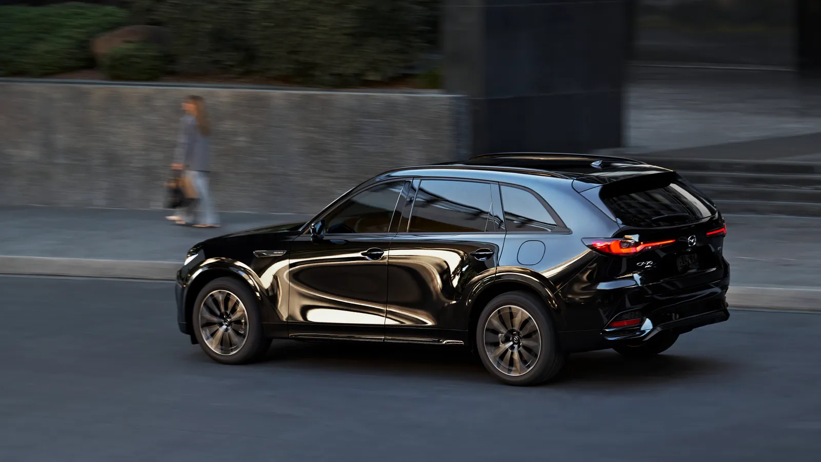 Mazda CX-70 2025 gris de profil sur une route, éclairé par la lumière dorée du coucher de soleil.